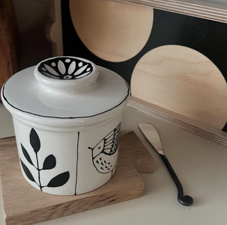 White ceramic butter crock with red floral patterns is hand-painted