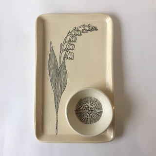 Beige ceramic tray with a black floral design and matching bowl on a white background
