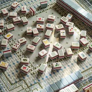 Mahjong game tiles arranged on a patterned mat, with a row of tiles visible along the top and right edges.