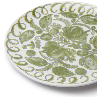 A close-up of a white ceramic plate decorated with a hand-painted green botanical pattern of leaves, flowers, and a decorative border.