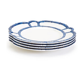 A stack of four blue and white melamine dinner plates with bamboo-style rims.