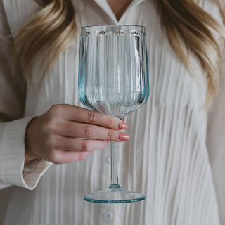 Person holding a clear blue-tinted plastic wine glass