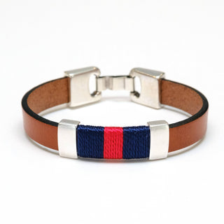 A brown leather bracelet with a central woven stripe design featuring navy blue and red threads, accented by silver-tone metal end caps and a buckle.