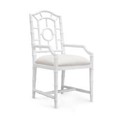 A white upholstered armchair with a geometric pattern on the backrest and faux bamboo detailing on the frame