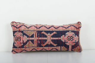 A rectangular vintage Turkish rug pillow with faded geometric patterns on a multicolored background.