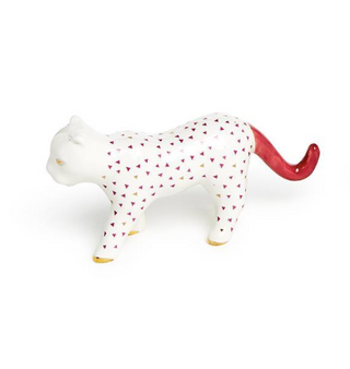 A white ceramic ring holder in the shape of an jaguar with red and gold geometric patterns.