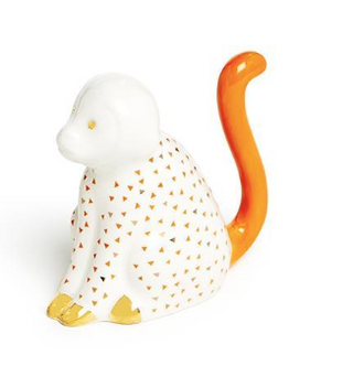 This ceramic ring holder is shaped like a monkey with whimsical gold geometric patterns, and an orange tail.