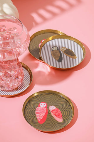 Set of coasters with owl designs on a pink surface