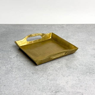 Gold rectangular tray with handles on a gray surface