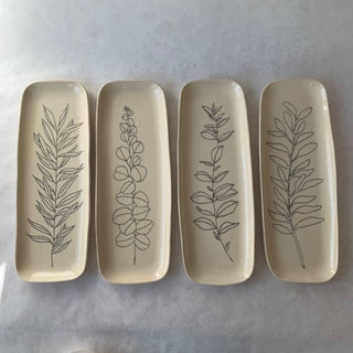 Four ceramic trays with leaf patterns on a light gray background