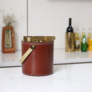 Brown leather ice bucket with gold accents on a white surface