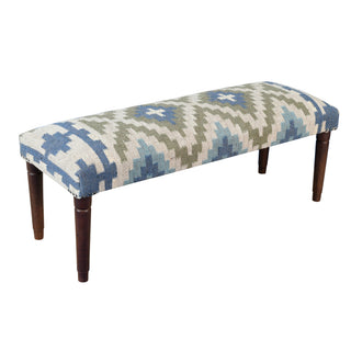 An upholstered bench with a geometric Southwestern-style pattern in blue, beige, and olive green, supported by four dark brown wooden legs, shown against a plain white background.