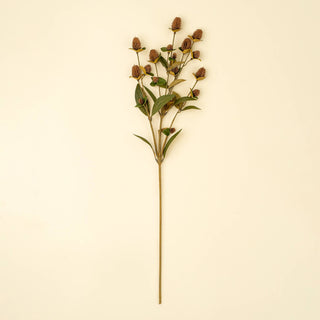Single stem of faux autumn flowers on a beige background