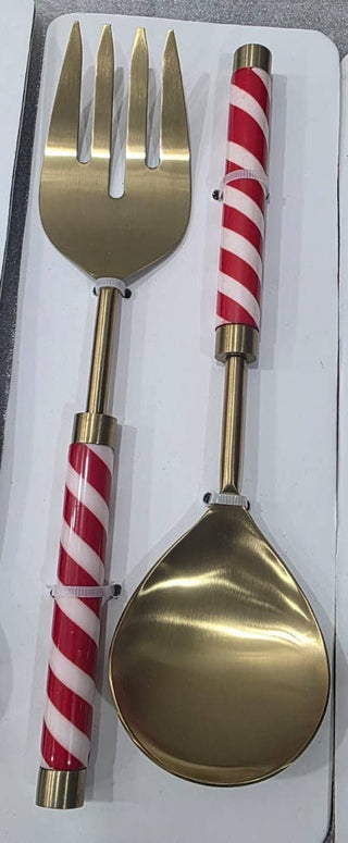 Gold-colored metal serving utensils, including a serving fork and a large serving spoon, both featuring red and white striped handles, presented in a white gift box.