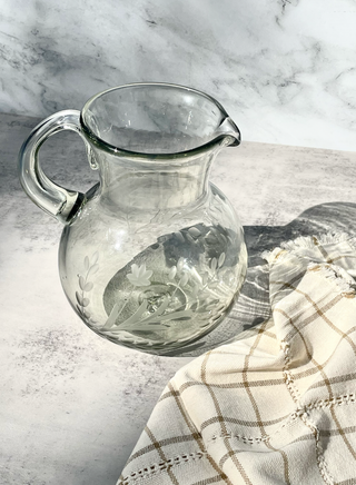 A clear, round, hand-etched blown pitcher with a handle makes the perfect serving vessel