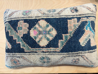 A square handwoven vintage Turkish rug pillow with a geometric pattern in navy blue, beige, and light blue.