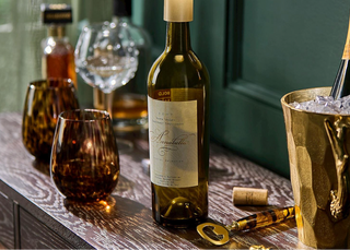 Wine bottle lamp on a wooden table with glasses and an ice bucket.