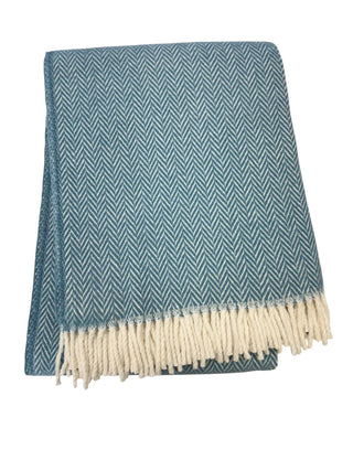 Blue and white herringbone patterned throw blanket with fringed edge on a white background
