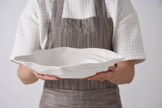 Person holding a white melamine oyster shaped serving dish