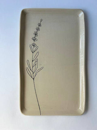 A rectangular ceramic serving tray with rounded corners, featuring a minimalist black line drawing of a botanical stem on the left side, set against a plain white background.