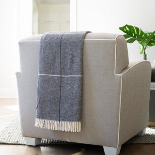 Beige armchair with a blue and white checkered throw blanket in a room with a plant.