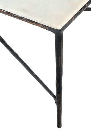 Close-up of a table corner showing a white marble top with a distressed dark metal frame and a single black leg on a white background.