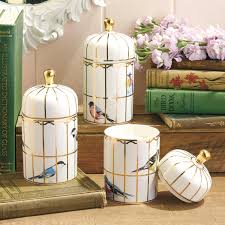 Decorative bird candle with gold accents on a wooden surface with books and flowers in the background.