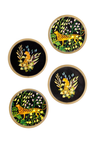 Four round decorative coasters with a black background, featuring a yellow cheetah, green foliage, and white flowers, arranged on a plain white background.