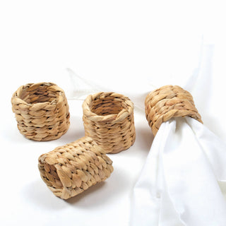 A set of beige natural rattan napkin rings displayed on a white surface.