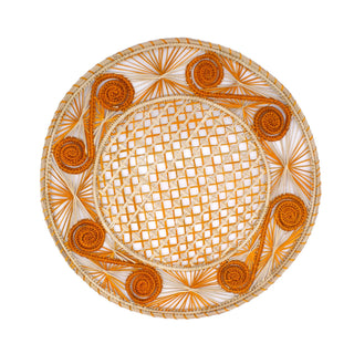 A round placemat with a vibrant orange color featuring a spiral design and made from woven natural straw.