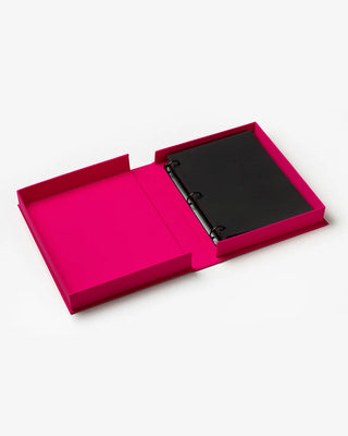 Black notebook inside a pink open box on a white background