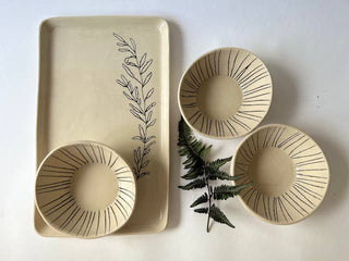 Set of ceramic dishes with black line art on a white background