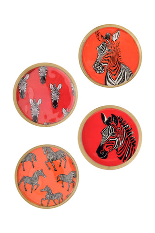 Four round decorative coasters with zebra designs on a white background. Two coasters feature black and white zebras on a bright red-orange background, and two feature gray zebras on a coral-orange background.