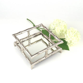 silver bamboo inspired cocktail napkin holder next to white flower