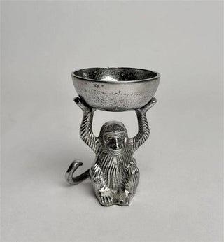 Metallic monkey figurine holding a bowl on a gray background