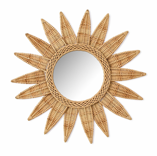 A round wicker wall mirror with a sunburst design, featuring natural rattan