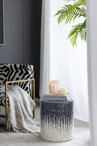 glass octagonal candle holder on a decorated side table with a candle lit inside