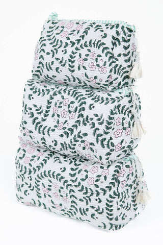 Three stacked quilted pouches with a white background, green leafy vine pattern, and small pink floral accents, featuring tassel trim on the sides.