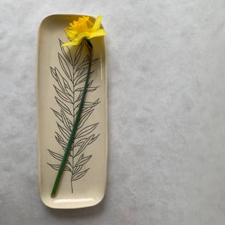 Rectangular ceramic dish with a yellow flower and black leaf design on a gray background