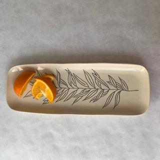 Rectangular ceramic plate with leaf design holding orange slices on a gray background