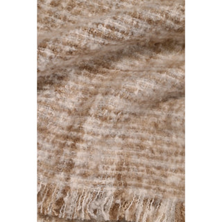 A close-up of a soft, textured woven fabric with a fringed edge, showing a marled pattern of beige, cream, and light brown tones.