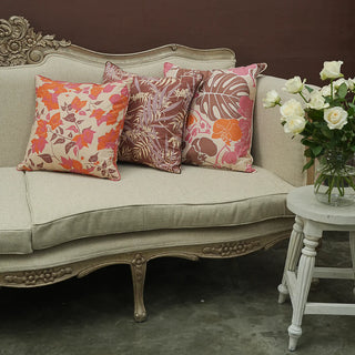 Decorative pillows on a vintage-style sofa with a side table and flowers.
