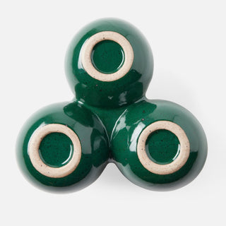 A glossy dark green ceramic three-bowl triptych vase with a speckled beige ring around the base of each bowl, shown on a clean white background.