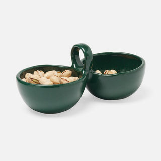 Two dark green ceramic bowls with integrated handles, one filled with pistachios and the other empty, on a light gray background.