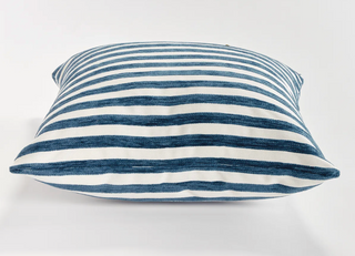 Striped pillow with blue and white horizontal stripes on a light gray background