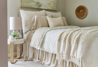 Neatly made bed with beige bedding in a bedroom setting.