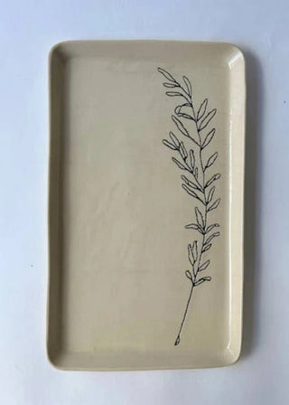 A rectangular beige ceramic tray with rounded corners, featuring a simple black line-art illustration of a leafy sprig on the right side, set against a plain white background.