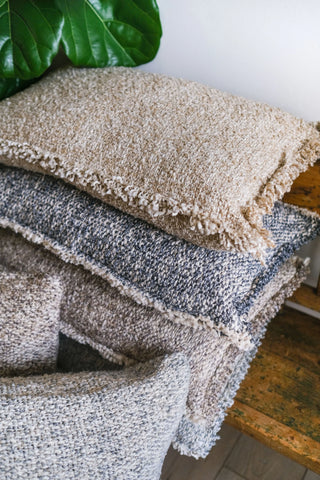 Stack of textured pillows with a plant in the background